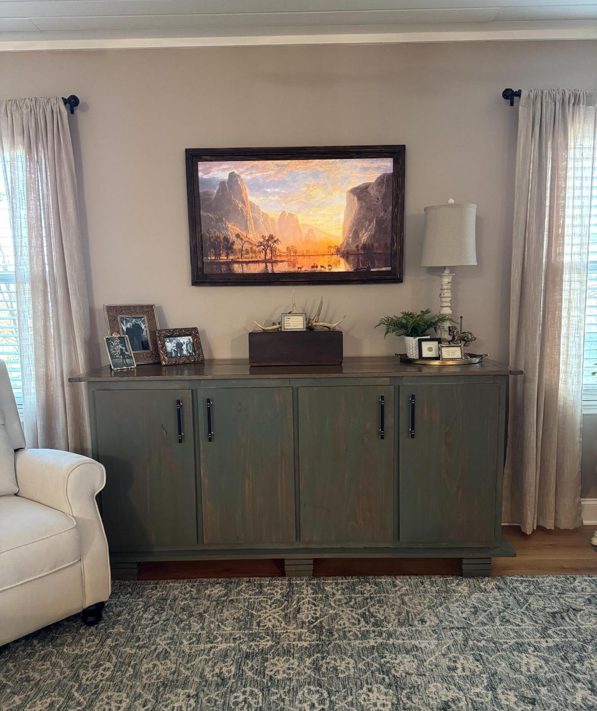 A framed TV above a green cabinet in a living room