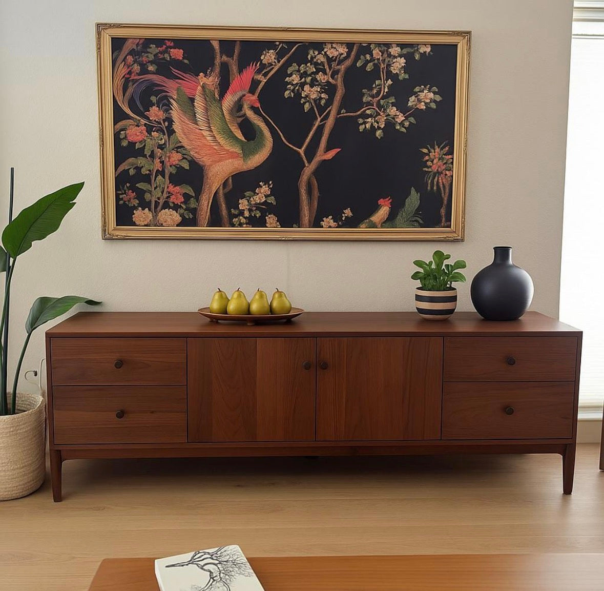 A gold framed TV with botanical artwork above a wood cabinet