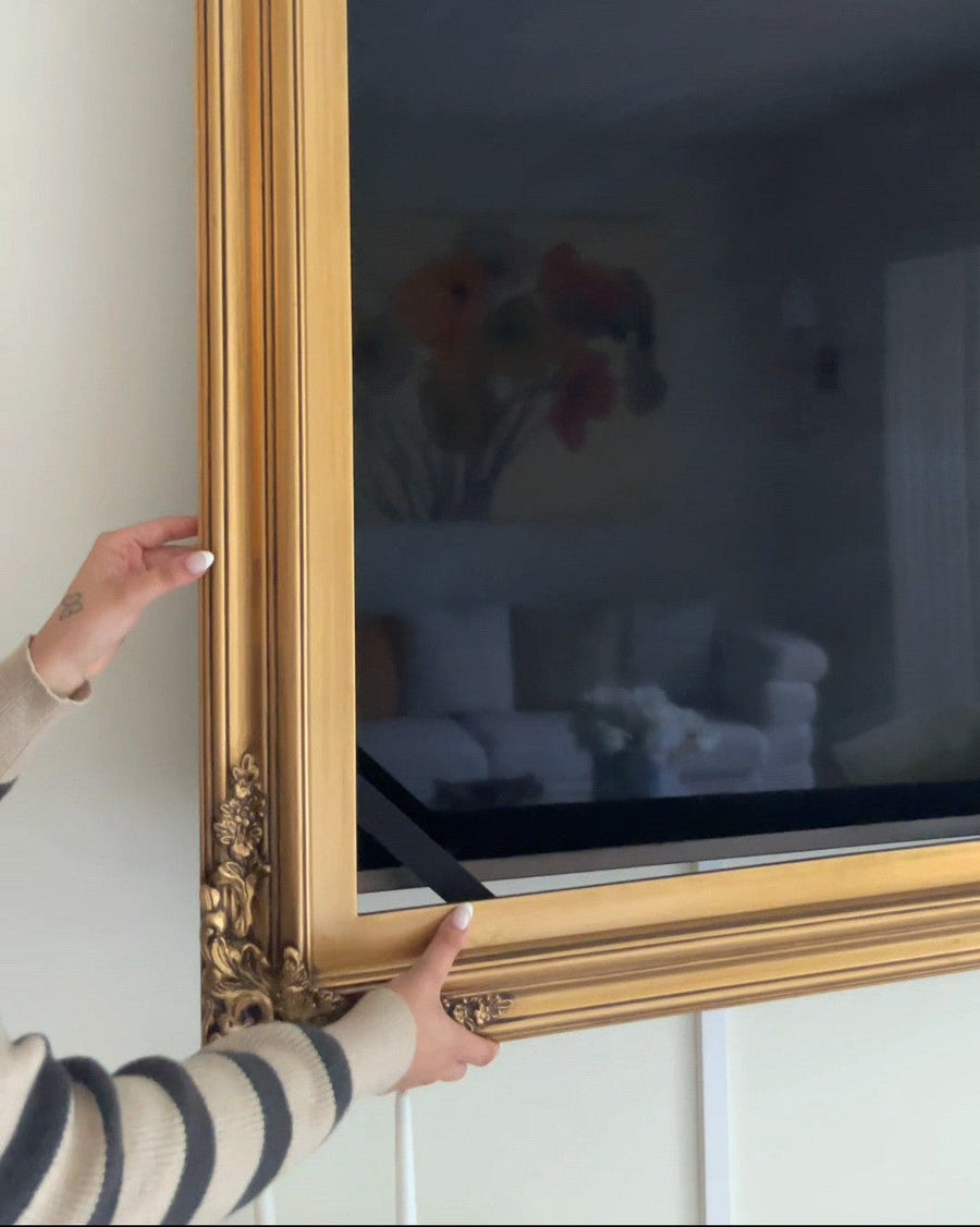 Placing the fully assembled gold frame around a television